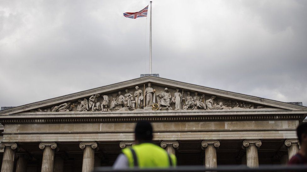 A Union Jack waves on top the British Museum as a security staff manages the flow of visitors in London