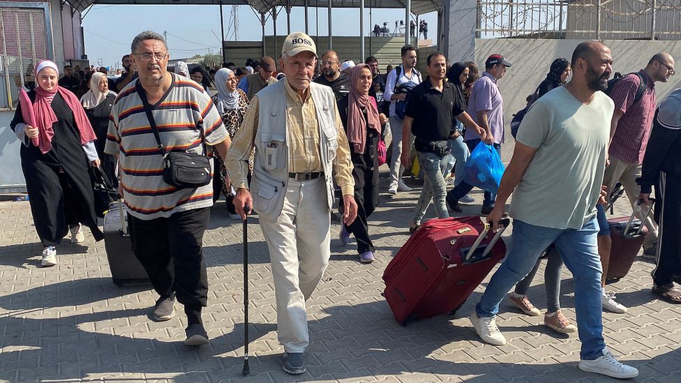 Palestinians with dual citizenship walk at the Rafah border crossing with Egypt