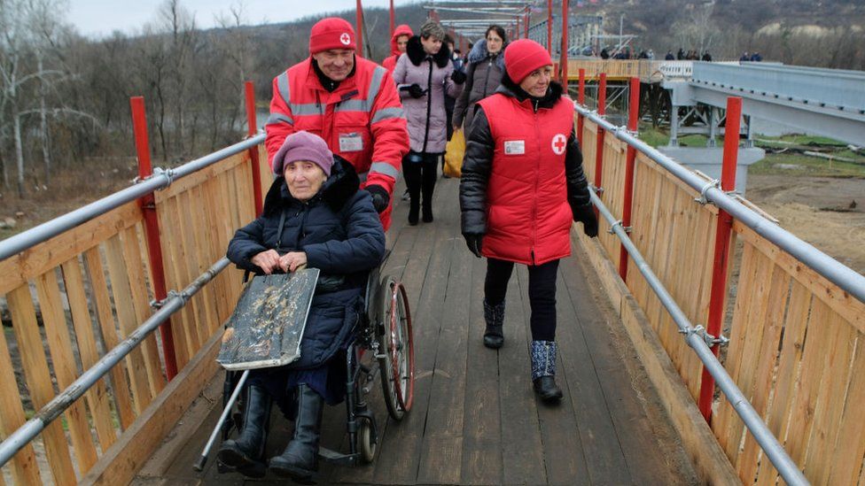 The sick and elderly crossing the bridge in eastern Ukraine, with the help of medics