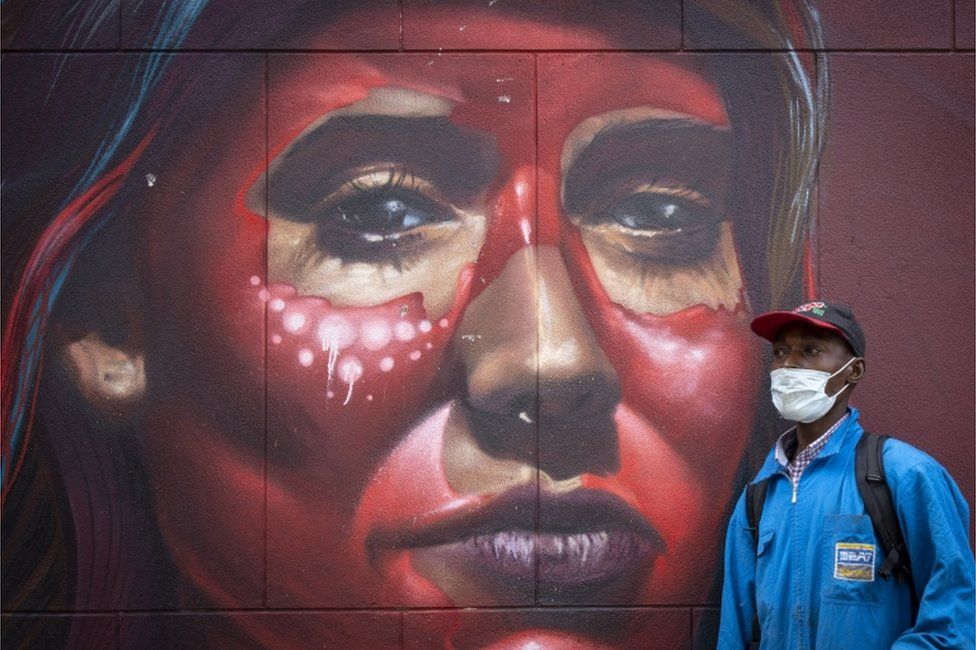 A man walks past a mural depicting a woman's face.