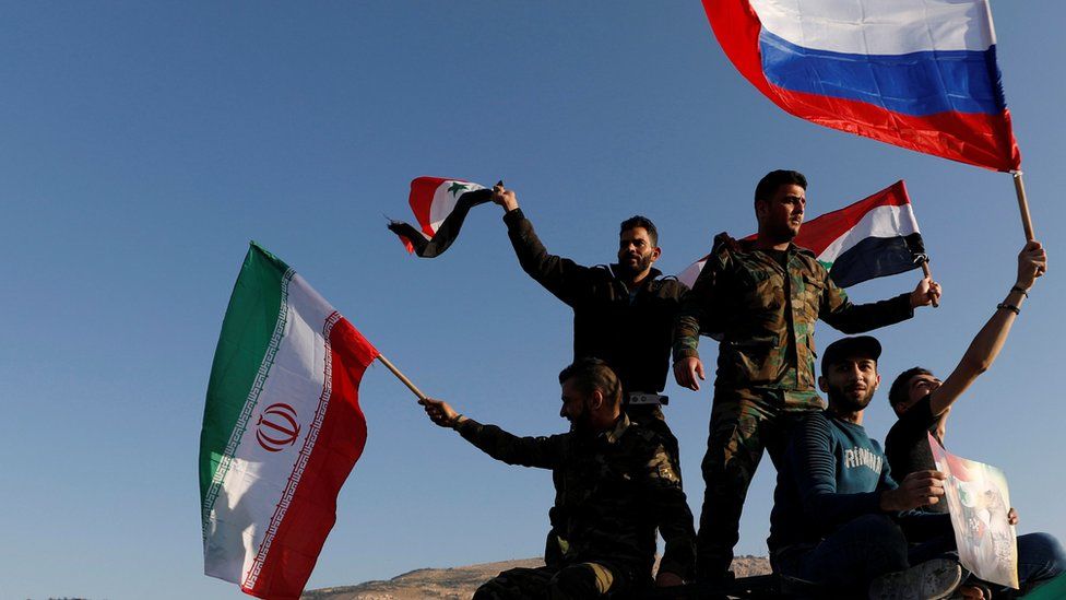 Syrians wave Iranian, Russian and Syrian flags during a protest against U.S.-led air strikes in Damascus, Syria April 14,2018.
