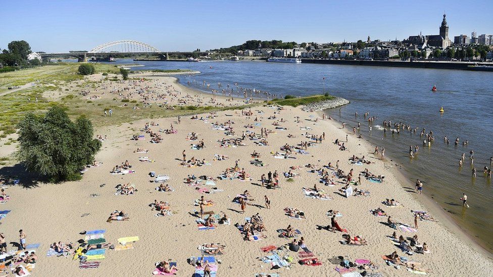 People enjoy the warm weather in the Waal river in Nijmegen, The Netherlands