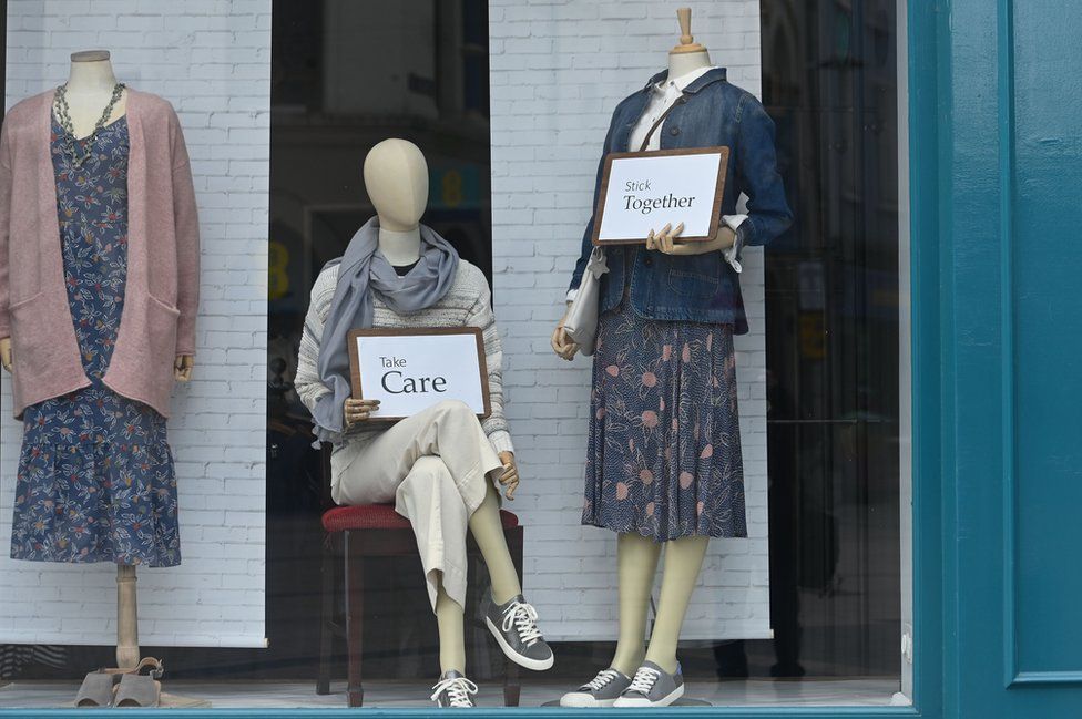 Mannequins in a Belfast clothing shop holding cards that read "take care" and "stick together"