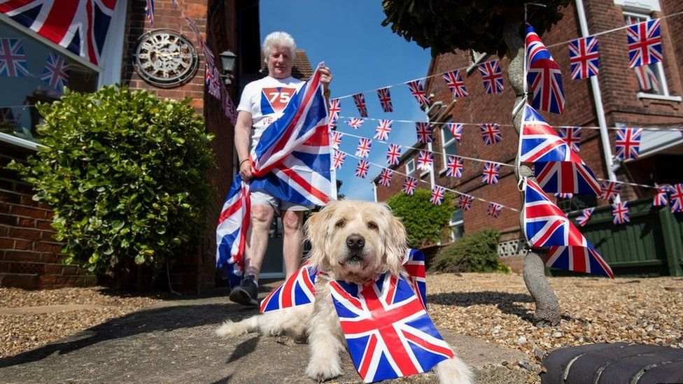 Pageant master of VE Day 75 Bruno Peek and his dog Wilson, as he decorates his house in Gorleston-on-Sea, Norfolk, with flags and bunting