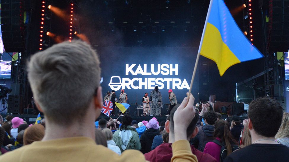 Fans with a Ukrainian flag watching Kalush Orchestra at the Eurovision village in Liverpool