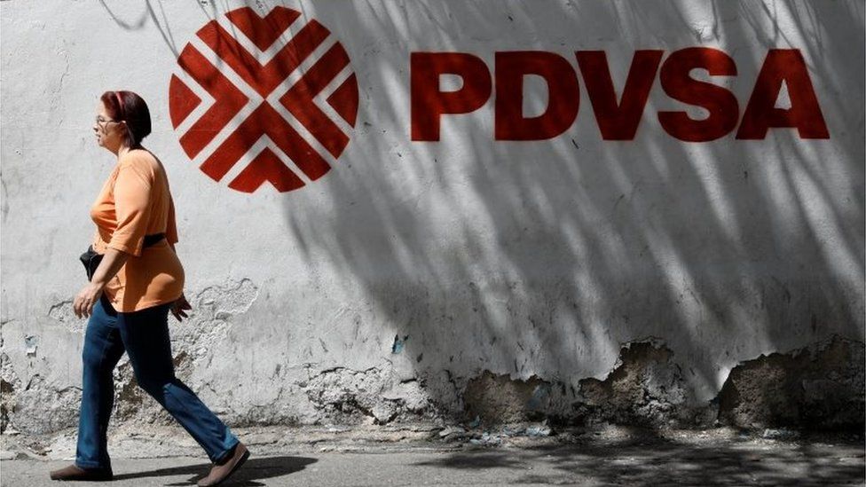 A woman walks past a mural with the corporate logo of the state oil company PDVSA in Caracas, Venezuela November 3, 2017