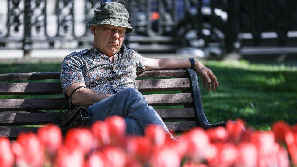A man sits on a bench looking sad.