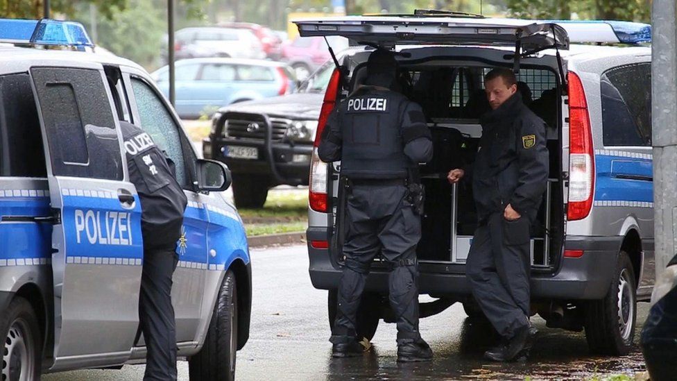 In this image taken from Nonstop News video, police officers surround an apartment in the eastern city of Chemnitz, Germany, Saturday Oct. 8, 2016