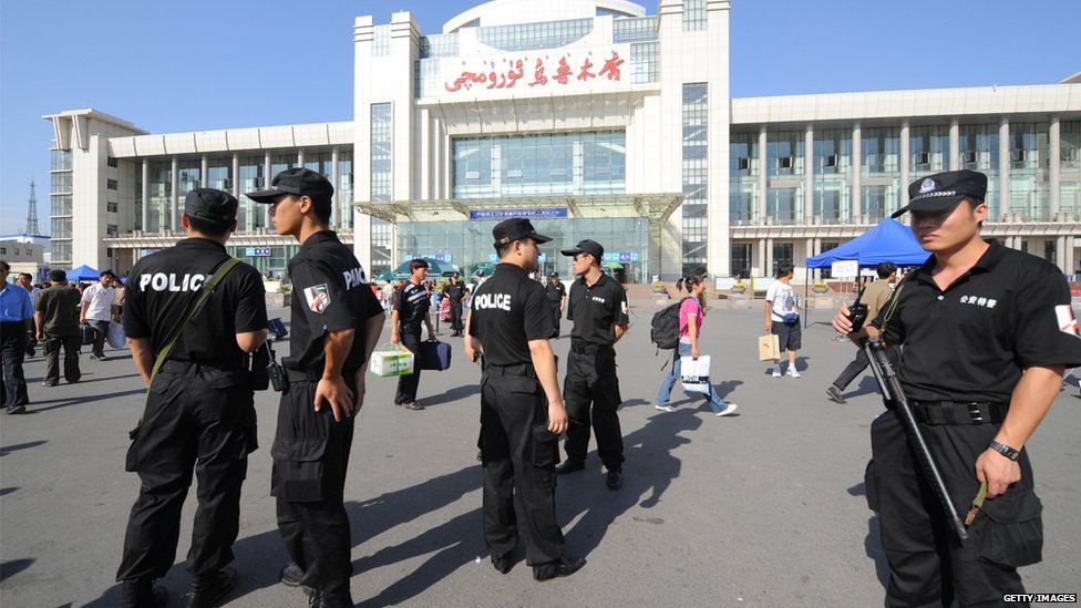 Chinese police maintain security as passengers arrive at the railway station in Urumqi, China's far-west Xinjiang region on 10 July, 2009
