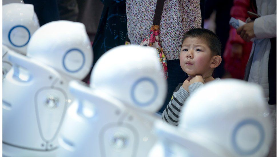 A boy looking at a display of robots during the World Robot Conference in Beijing
