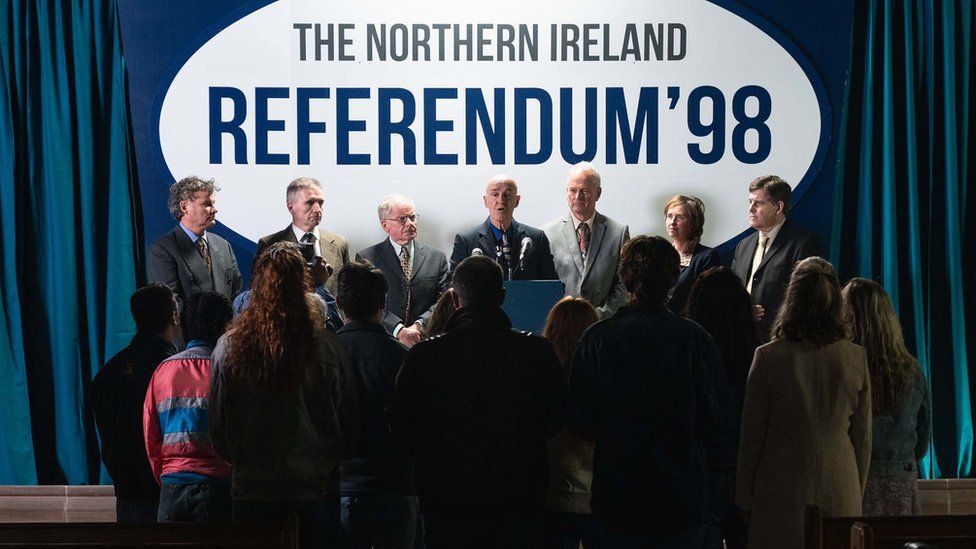Promotional still from Derry Girls showing a sign publicising the Northern Ireland Referendum 1998