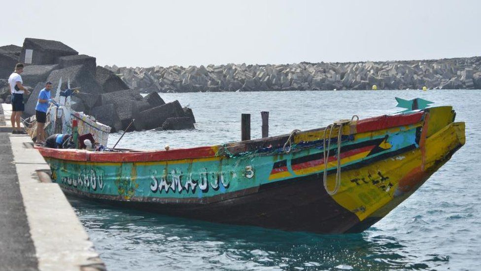 A wooden boat that arrived in Spain's Canary Islands carrying 280 people on 3 October 2023. The boat is painted green and yellow. It looks big enough to safely hold a few dozen people.