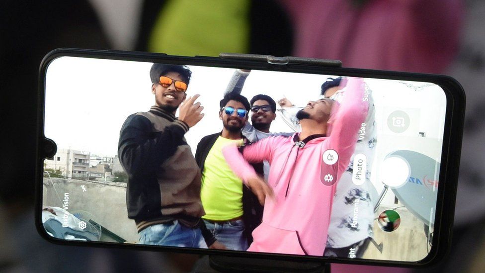 Youths act in front of a mobile phone camera while making a TikTok video on the terrace of their residence in Hyderabad, February 2020
