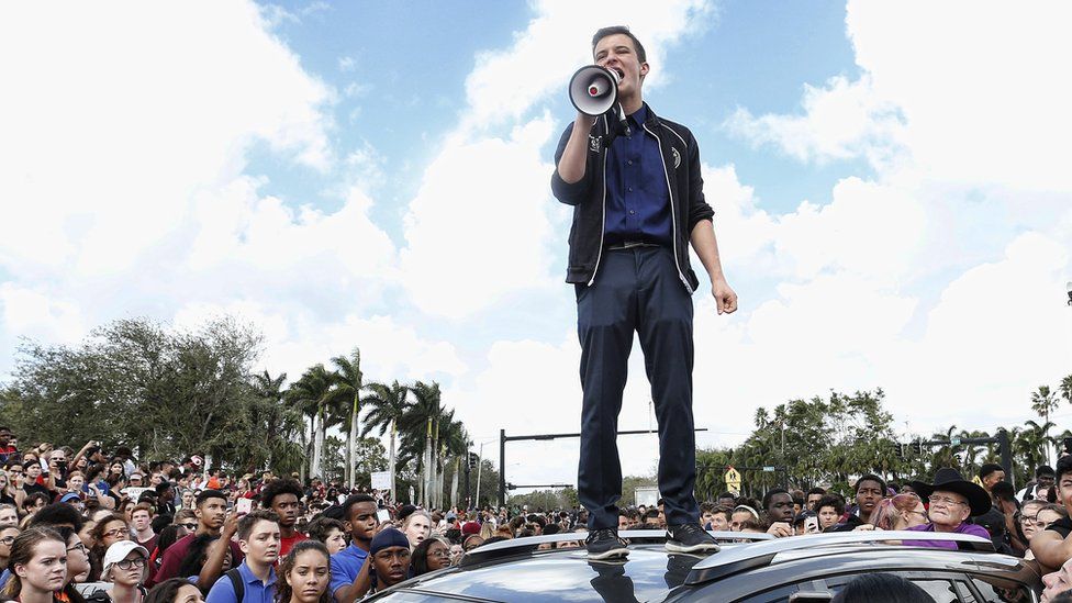 Cameron Kasky standing on a car
