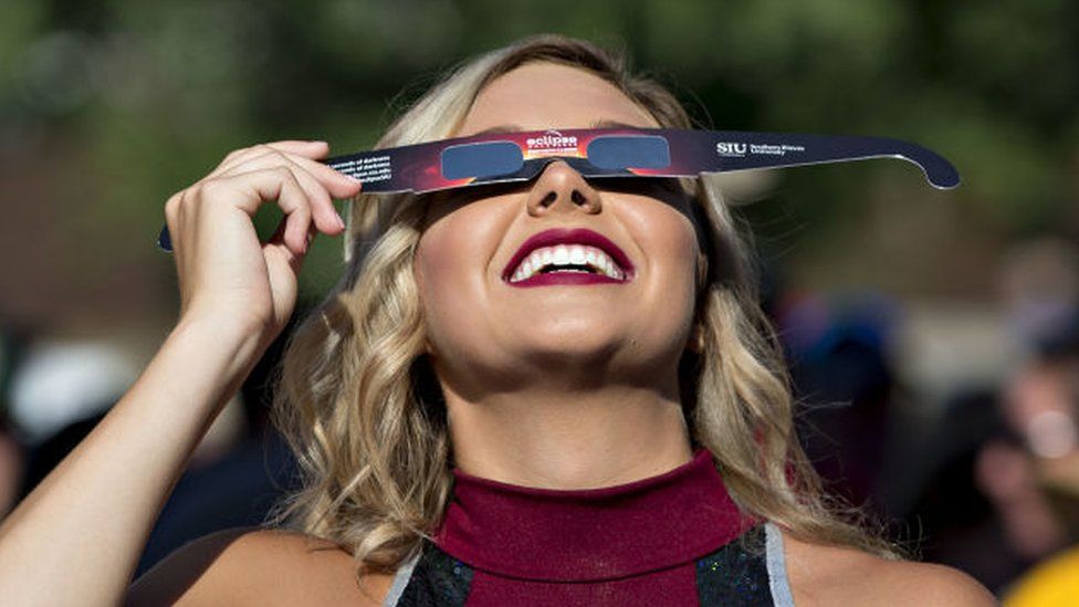 Cheerleader with eclipse glasses