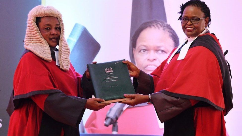 Kenya's Chief Justice Martha Koome (R) receives the instruments of power and state of judiciary report from Deputy Chief Justice Philomena Mwilu (L), at the ceremony for assumption of office for the Chief Justice, outside the Supreme Court buildings in Nairobi on May 24, 2021