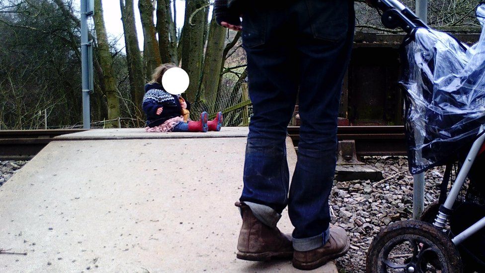 A parent places a baby on the railway track in Harlech to take a photo