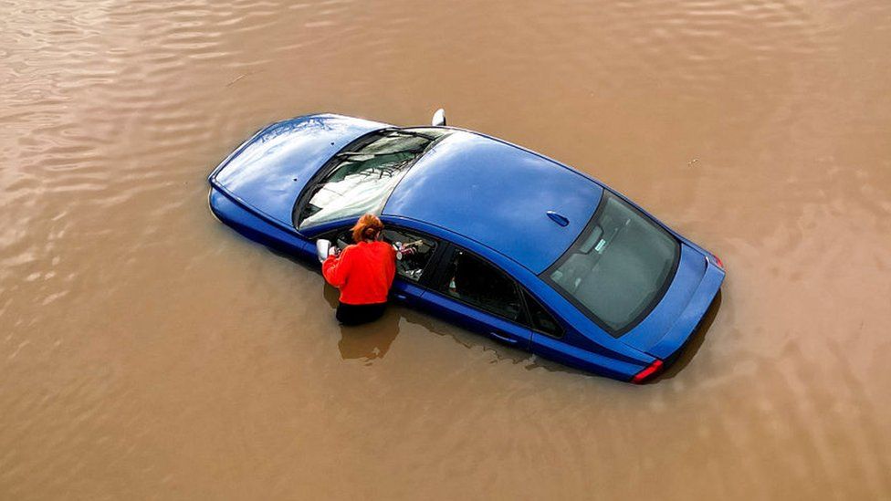 A woman checks on a flooded car in car park in Worcester city centre on January 03, 2024 in Worcester, England.
