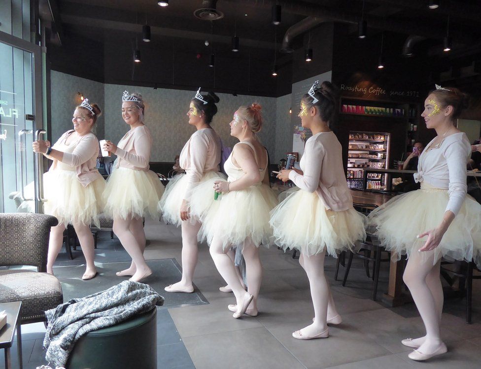 A group of women walking in a line are dressed in ballerina costumes