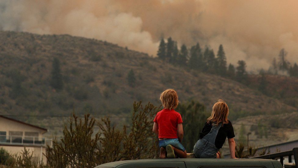 Местные дети наблюдают за тушением пожара среди густого дыма от лесного пожара в Игл-Блафф