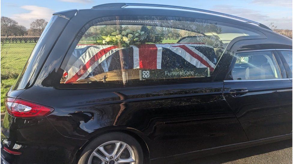 A hearse carrying Mr English's union flag-draped coffin