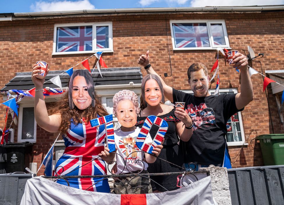 A family wear masks depicting members of the royal family, at a Jubilee Street Party in Trafford, Manchester, on 4 June 2022