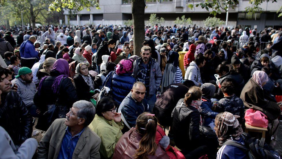 In this file photo taken Wednesday, 30 September 2015, hundreds of migrants and refugees wait for Berlin's State Office of Health and Welfare, the cities central registration point for asylum seekers in Berlin, Germany.