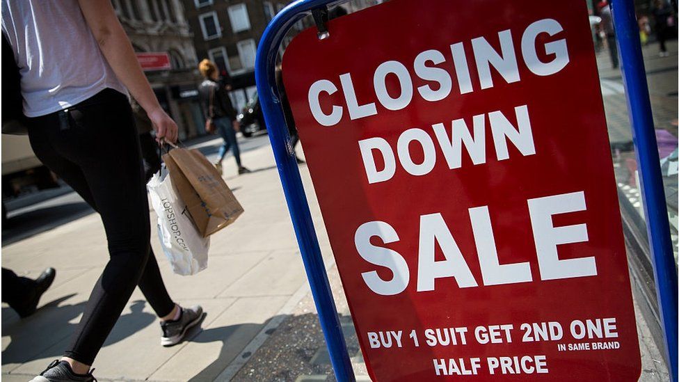 A closing down sale sign is seen outside a men's clothing shop on Oxford Street