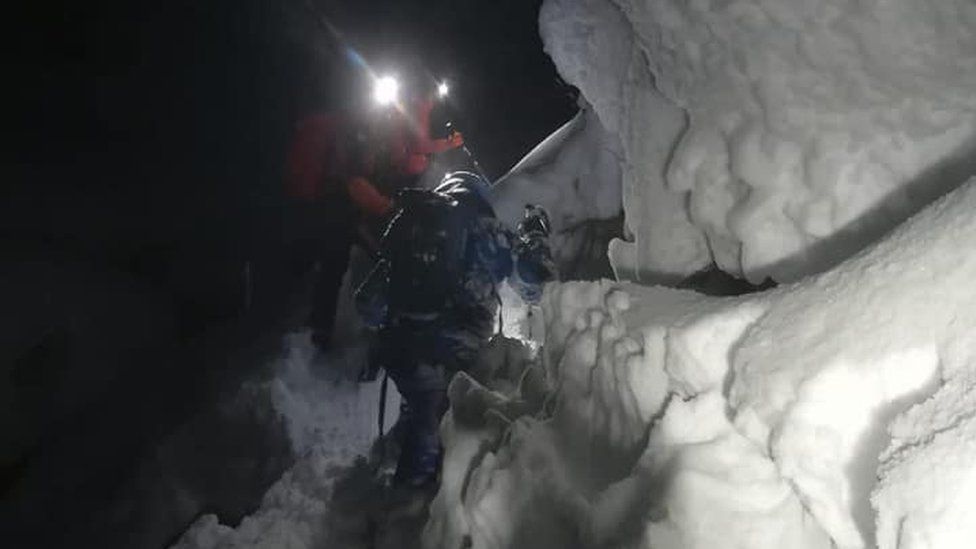 Rescuers climb through deep snow to reach a Polish snowboarder