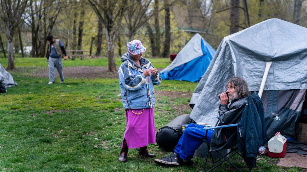 Homeless senior citizens Kim Morris and Kevin Gevas call a homeless advocate from Mint at Tussing Park in Grants Pass, Oregon on Thursday March 28, 2024