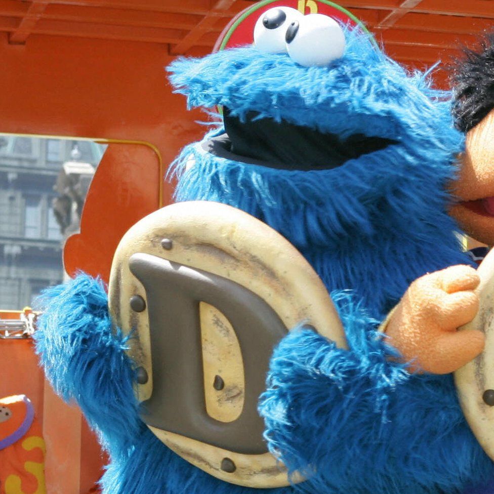 The Cookie Monster from Sesame Street holds up the letter D
