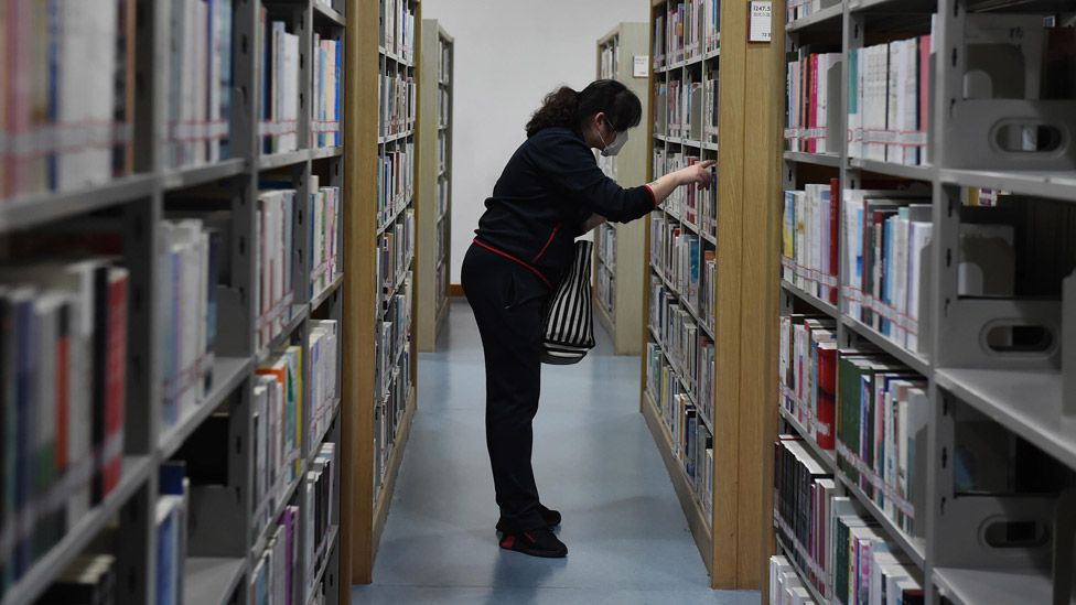 A woman looking at books on a shelf