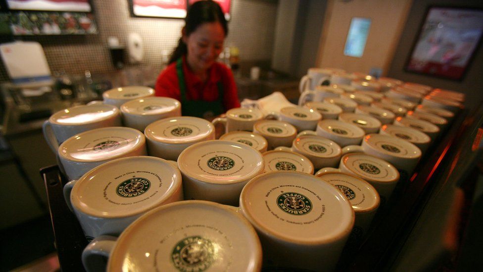 A Starbucks employee works next to a shelf of up-turned mugs in a store on December 18, 2007 in Chongqing, China.
