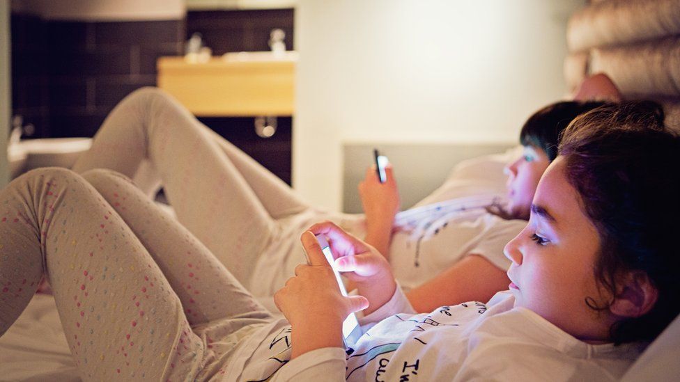 Two girls on mobile phones in bed