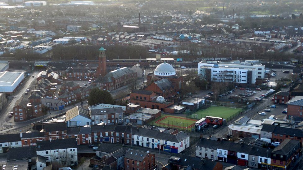 A drone view of terraced housing and the dome of St John the Baptist church in Rochdale