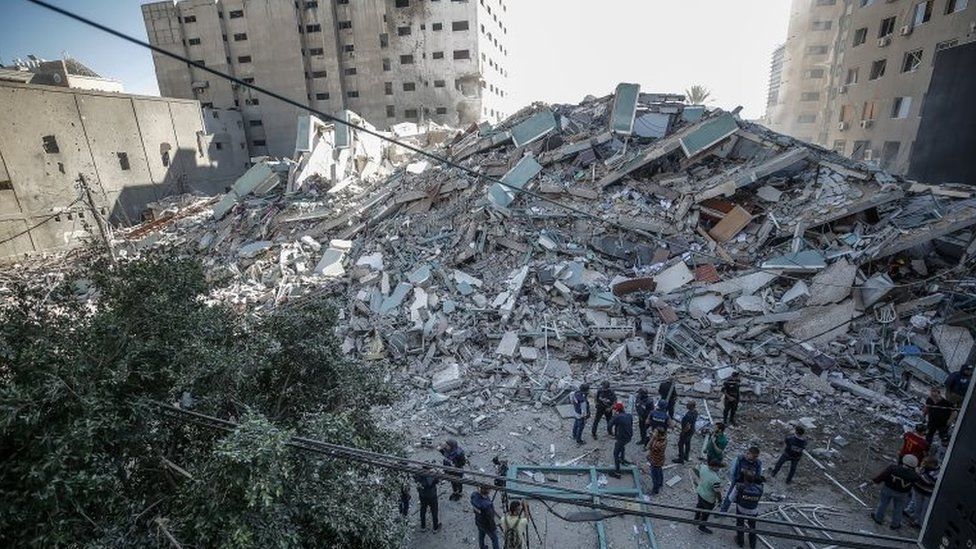 Palestinians inspect the rubbles after an Israeli air strike hit Al-Jalaa tower, which houses apartments and several media outlets, including the Associated Press and Al Jazeera, in Gaza City, 15 May 202