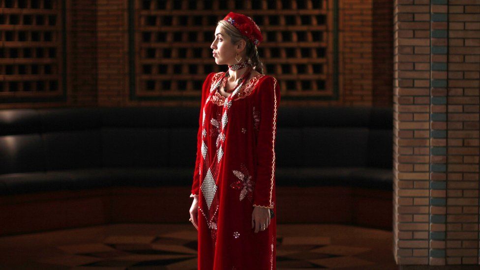 A woman in traditional dress waits on October 22, 2011 for the departure of US Secretary of State Hillary Clinton, who spoke at a town hall discussion at the Ismaeli Center in Dushanbe