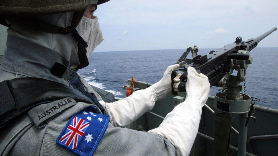 A member of he Royal Australian Navy mans his machinegun during an exercise in the South China Sea