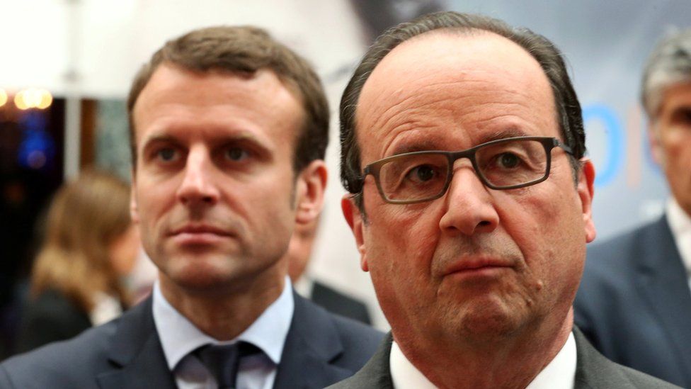 French President Francois Hollande stands in front of French economy minister Emmanuel Macron