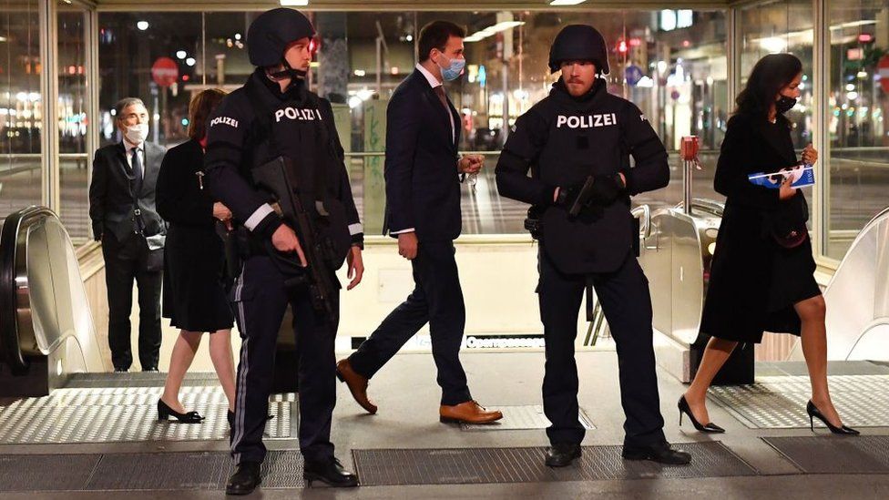 Opera guests walk past policemen after leaving the state opera in Vienna