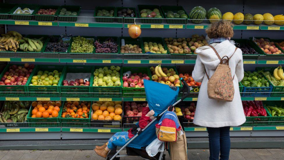 Shopper looking at fruit in supermarket aisles