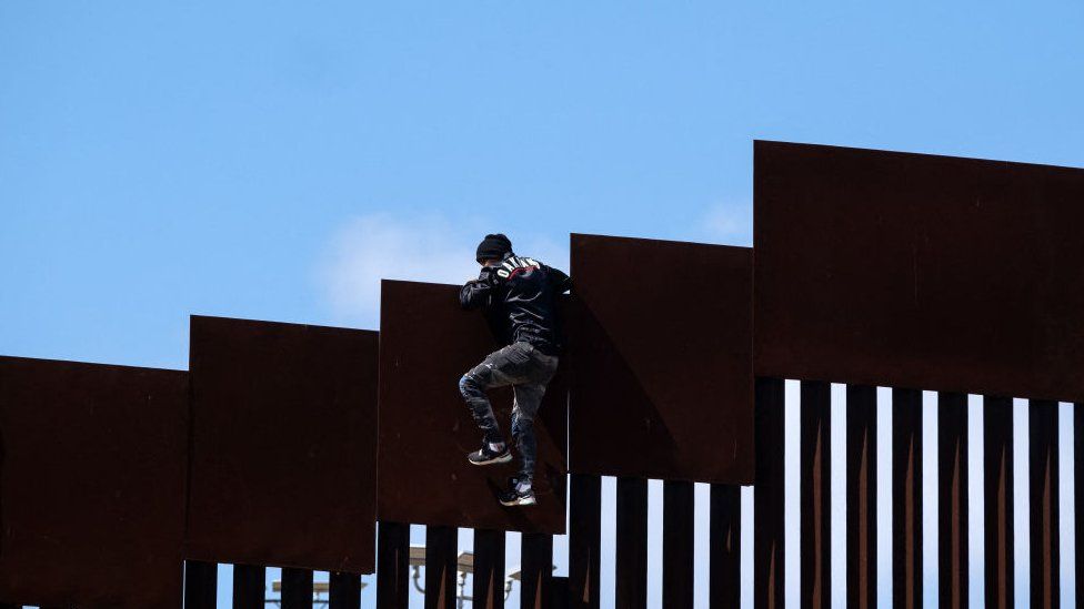 Мужчина перелезает через пограничный барьер в Калифорнию, 10 мая 2023 г.