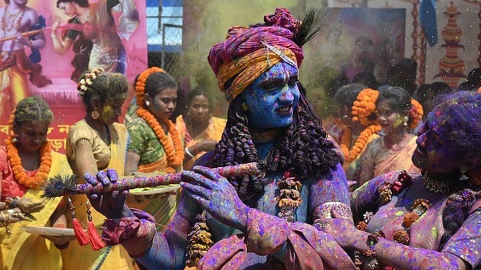 Youths smeared in coloured powder and dressed as Lord Krishna (L) and deity Radha (R) celebrate with others the Holi festival, the Hindu spring festival of colours, in Kolkata on March 17, 2022.
