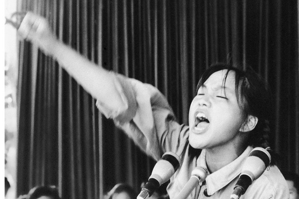 Close up image of a young woman calling out to fellow Red Guards from a platform in Beijing's Tiananmen Square on 10 August 1966