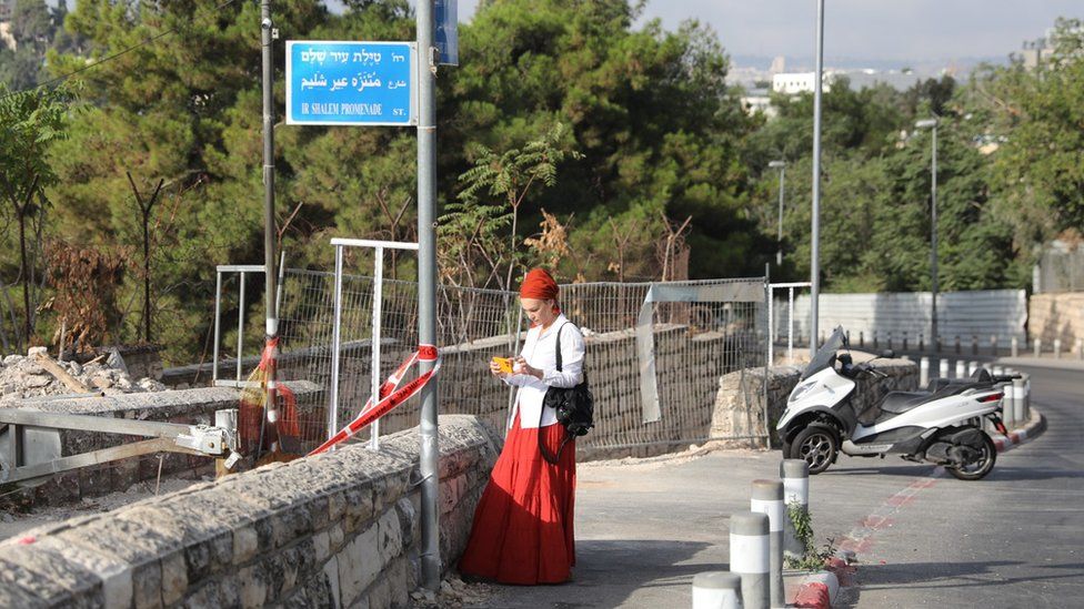 A woman takes a photo at the scene of a shooting attack in Jerusalem (14 August 2022)