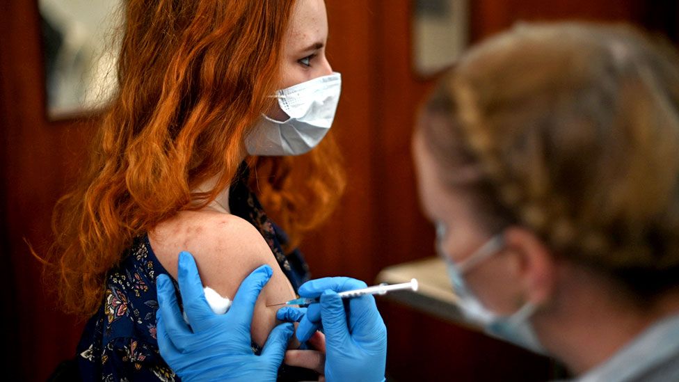A member of the public receives a dose of a Pfizer Covid-19 vaccine jab at a temporary coronavirus vaccination centre set up inside St John's Church in west London on 4 December 2021