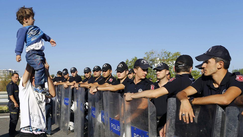 Boy looks over heads of Turkish police blocking migrants near the border with Greece - 19 September