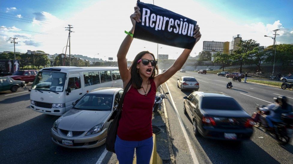 A student shouts slogans against Venezuelan President Nicola Maduro. She holds a sign saying 'repression' during a protest on the main highway in Caracas