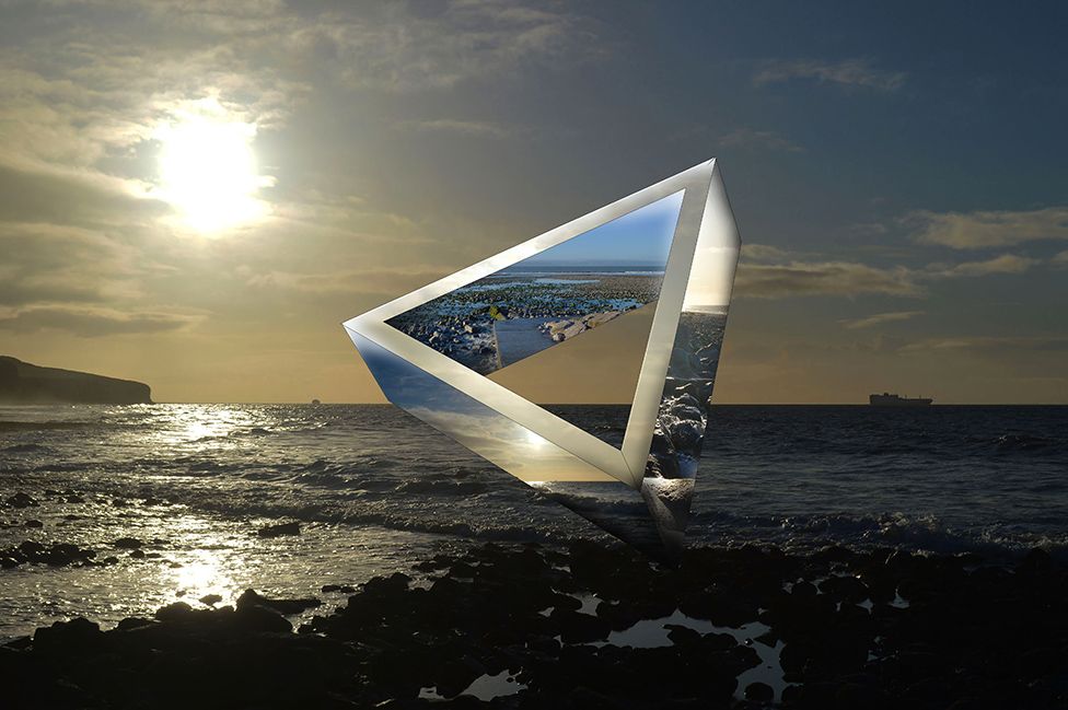 A shot of a triangular art piece in the middle of the ocean