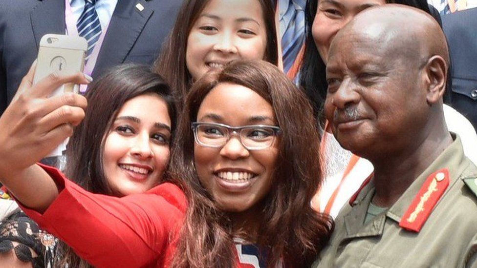 Dr Jamechia Hoyle holds her smartphone, as she attempts to take a selfie with Ugandan President, Yoweri Museveni